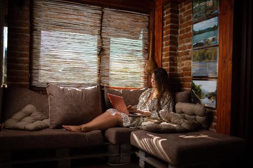a woman sitting on a couch with a laptop at Holiday Home Drinsko svitanje in Gornja Trešnjica