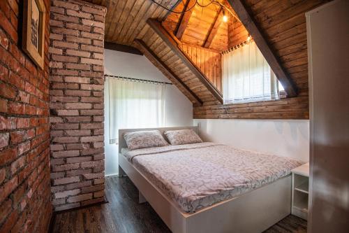 a bedroom with a bed and a brick wall at Holiday Home Drinsko svitanje in Gornja Trešnjica