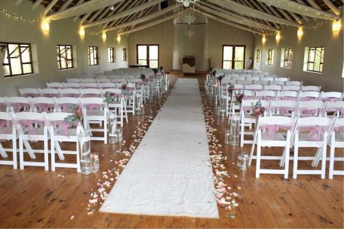 a room with white chairs and a aisle with flowers at Umuzi Lodge in Secunda