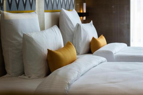 two beds with white pillows and yellow pillows at Novotel Guwahati GS Road in Guwahati
