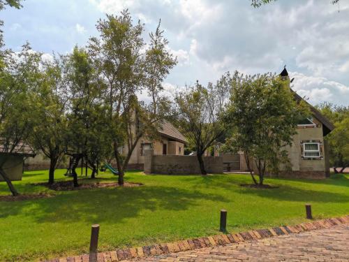 a house on a green yard with trees at Umuzi Lodge in Secunda