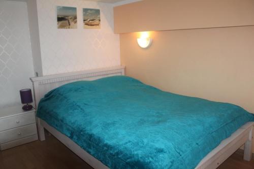 a bedroom with a bed with a blue blanket at Apartament Słoneczny in Międzyzdroje