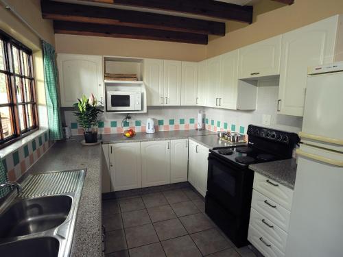 a kitchen with white cabinets and a black stove top oven at Petal Faire Cottage in Pretoria