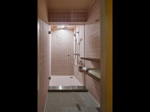a bathroom with a shower with pink tile at 9h nine hours Nakasukawabata Station in Fukuoka
