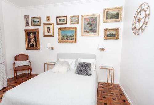 - une chambre avec un lit blanc et des photos encadrées sur le mur dans l'établissement Charmant 2 pieces frontiere Monaco, à Beausoleil