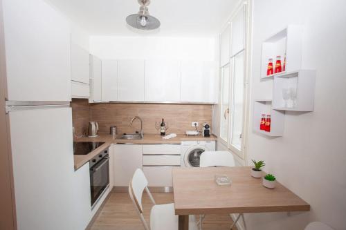 une cuisine avec des armoires blanches et une table en bois dans l'établissement Magnifique 2 pieces frontiere Monaco, à Beausoleil