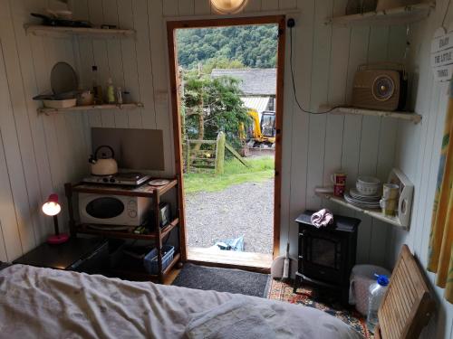 a room with a bed and a door to a yard at Stybeck Farm Shephards Hut in Thirlmere