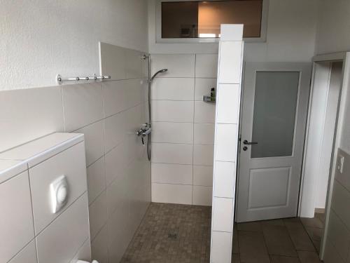 a white bathroom with a shower and a door at Hof Jüttmann in Badbergen