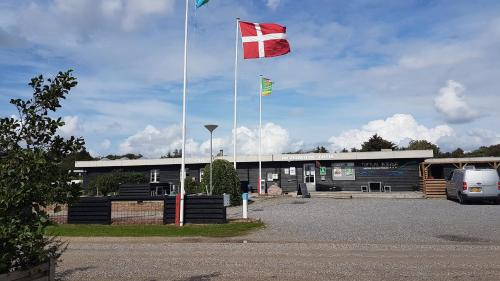 two flags are flying in front of a building at Toftum Bjerge Camping & Cottages in Humlum