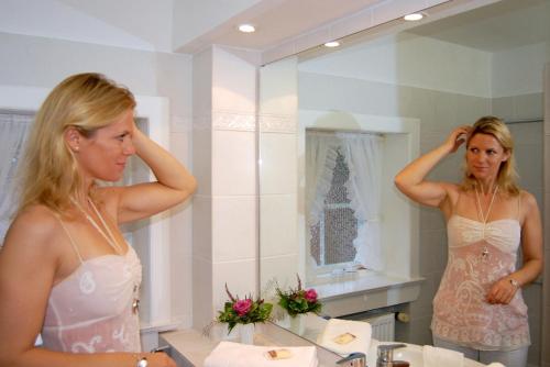 una mujer parada frente a un espejo de baño en Reetdachhus an de Diek en Sankt Peter-Ording