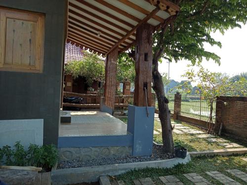 een houten pergola met een boom naast een huis bij JOGLOPARI GuestHouse bukan untuk pasangan non pasutri in Bantul