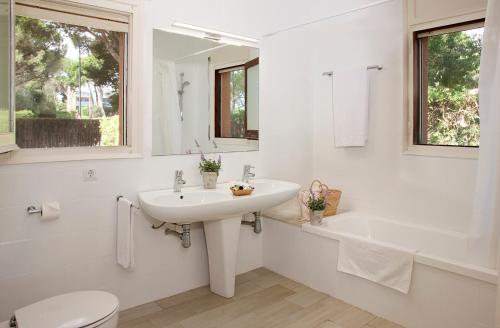 a white bathroom with a sink and a tub and a toilet at Villa Familiar by La Costa Resort in Pals