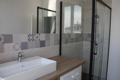 een badkamer met een wastafel en een glazen douche bij L'ALBATROS in Granville