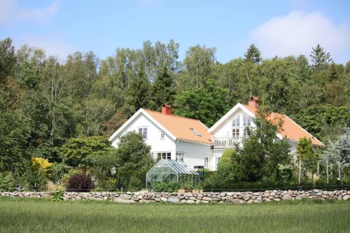 a white house with a stone wall and trees at Apartment in the countryside in Tossene Hunnebostrand in Hunnebostrand