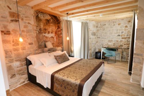 a bedroom with a bed in a room with a stone wall at Villa Teuta in Trogir