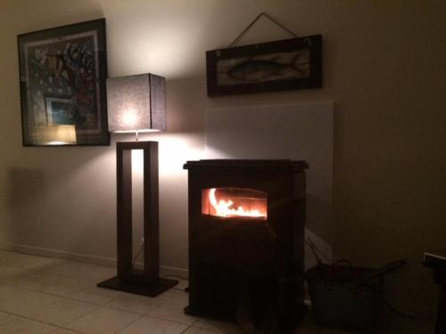 a living room with a fireplace and a lamp at Adorable Penty en pierres en bord de mer in Tréogat