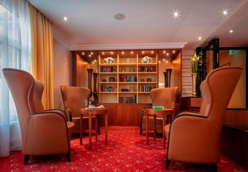 a waiting room with chairs and a book shelf at Hotel Schweizer Hof Thermal und Vital Resort in Bad Füssing