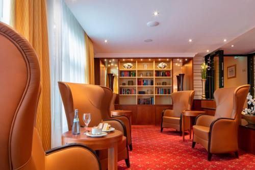 a waiting room with chairs and a table and a book shelf at Hotel Schweizer Hof Thermal und Vital Resort in Bad Füssing