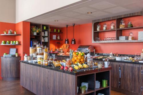 a kitchen with orange walls and a counter with fruit on it at Best Western Premier Le Masq H&ocirc;tel in La Rochelle