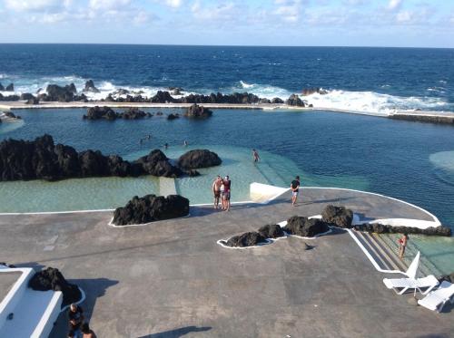 people swimming in a swimming pool near the ocean at Pensão Fernandes in Porto Moniz