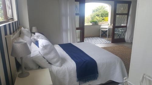 a bedroom with a blue and white bed with a window at Lucky Fishes in Southbroom