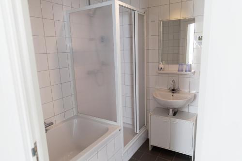 a white bathroom with a sink and a tub and a toilet at Hotel Vierhouten in Vierhouten