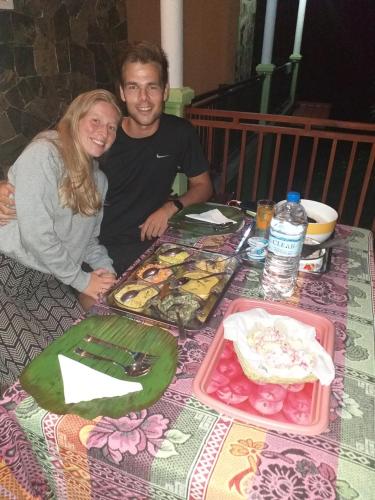 a man and a woman sitting at a table with food at Serene Homestay Ella in Ella