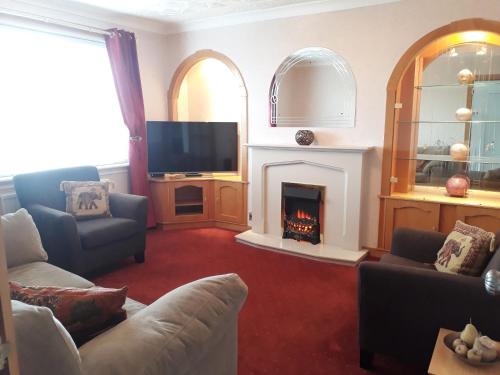 a living room with a fireplace and a tv at Hilltop House in Airdrie