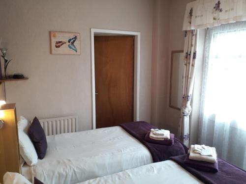 a bedroom with two beds and a window and a door at The Inn Place in Skegness