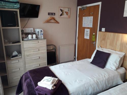a bedroom with a bed and a dresser and a tv at The Inn Place in Skegness