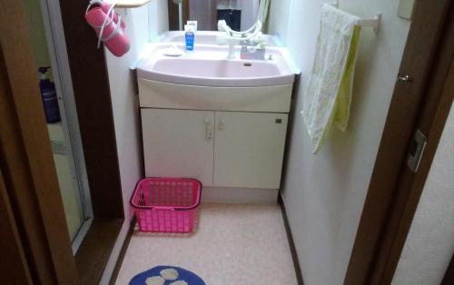 a small bathroom with a sink and a pink basket at FukuokaKoryou GuestHouse in Fukuoka