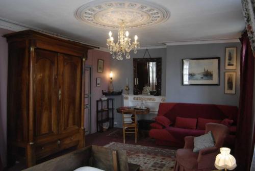 a living room with a red couch and a chandelier at Chambres d'hôtes Logis Du Jerzual in Dinan