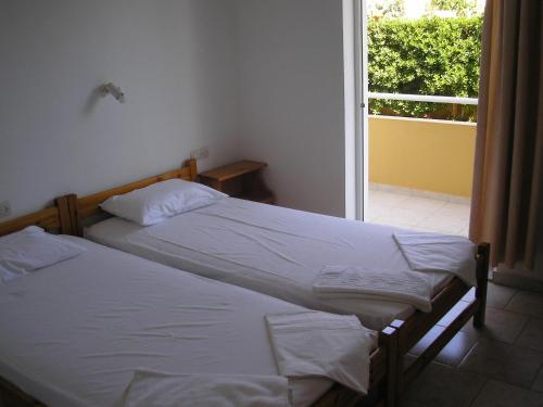 2 camas individuales en una habitación con ventana en Dimitra Apartments, en Gouves