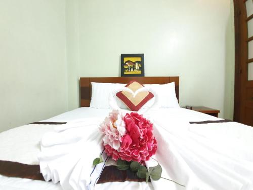 a white bed with a heart pillow and a pink flower at Khách sạn Trường Sơn in Ho Chi Minh City