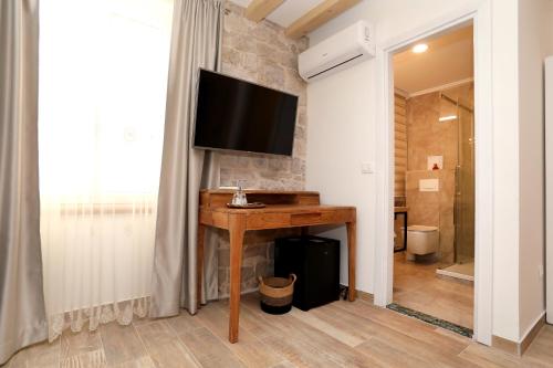 a bathroom with a table with a television on a wall at Villa Teuta in Trogir