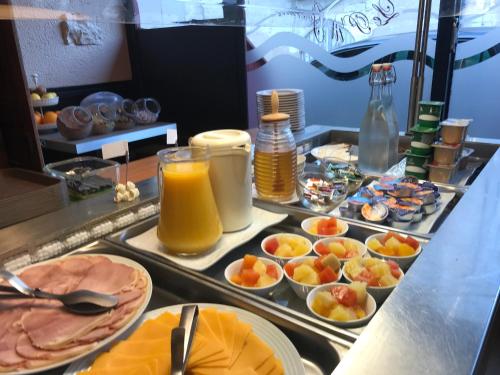 ein Buffet mit Speisen und Orangensaft in der Unterkunft Hotel du Centre - Restaurant le P'tit Gourmet in Tonnerre