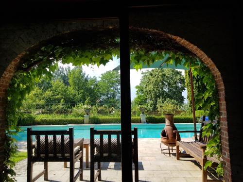 an archway with two chairs and a table and a pool at Le Bocage Fleuri in Mons