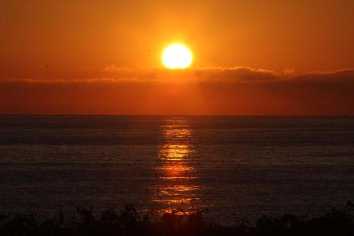 a sunset over the ocean with the sun in the sky at Hotel Águas Vivas in Caraguatatuba