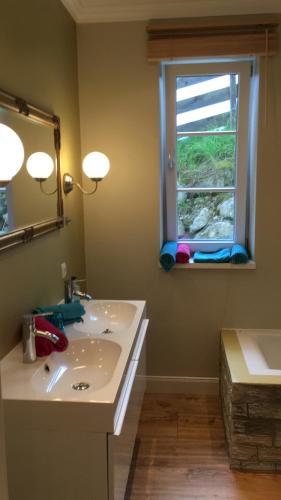 a bathroom with a sink and a mirror and a window at Landhaus Roidergütl in St. Wolfgang