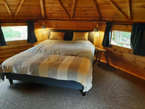 a bedroom with a bed in a wooden cabin at La cabane de l'Atelier in Bomal