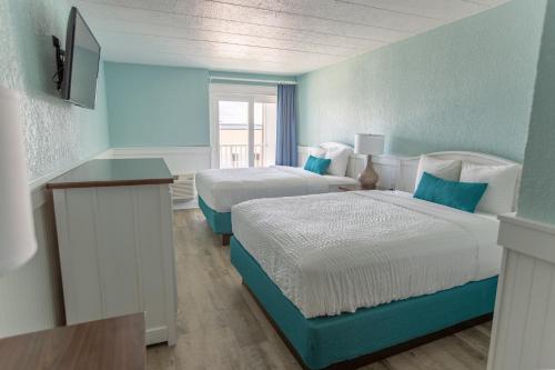 a blue room with two beds and a television at John Yancey Oceanfront Inn in Kill Devil Hills