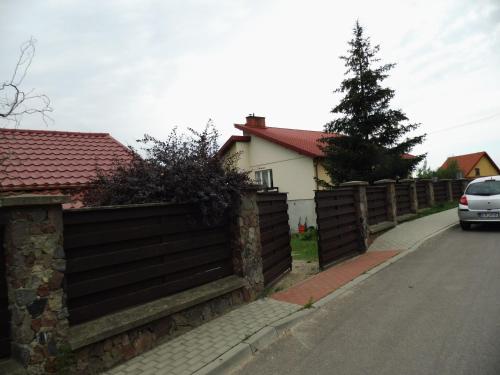 a fence in front of a house with a car at Kwatera do wynajęcia in Gołdap