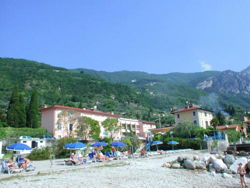 a group of people sitting under umbrellas on a beach at Hotel Lido in Gargnano