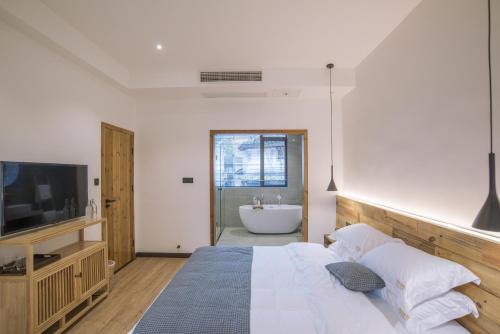 a bedroom with a bed and a tub and a television at BaHaoBieYuan in Fenghuang