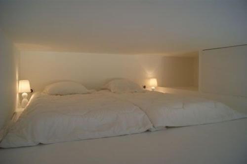 - un lit blanc dans une chambre avec deux lampes dans l'établissement Le Gîte de l'Océan, à Lège-Cap-Ferret