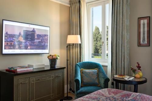 a hotel room with a bed and a chair and a window at Rocco Forte Hotel De La Ville in Rome