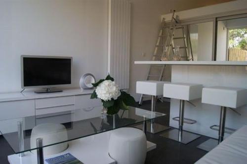 a living room with a glass table and a television at Le Gîte de l'Océan in Lège-Cap-Ferret