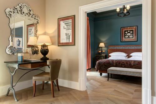 a bedroom with a bed and a desk and a mirror at Rocco Forte Hotel De La Ville in Rome