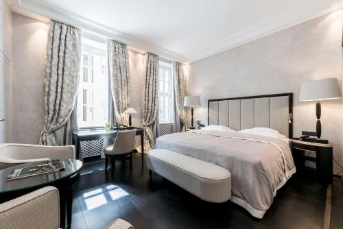 a bedroom with a large bed and a table and chairs at Hotel Bayerischer Hof in Munich