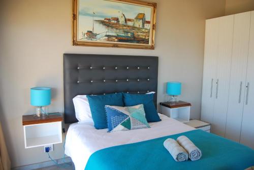 a bedroom with a large bed with blue pillows at Wilderness Ocean View Cottage in Wilderness